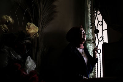 Side view of woman looking at window