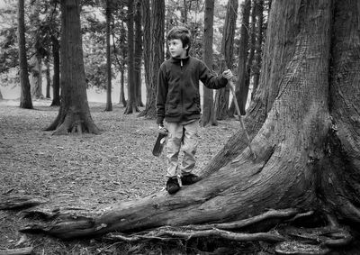 Full length of boy standing by tree on ground