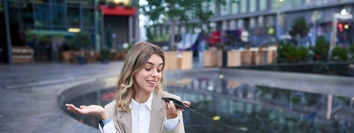 Portrait of young woman standing in city