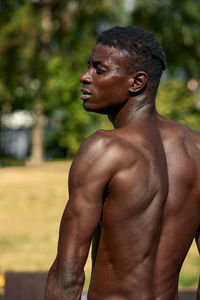 Side view of shirtless man exercising in park