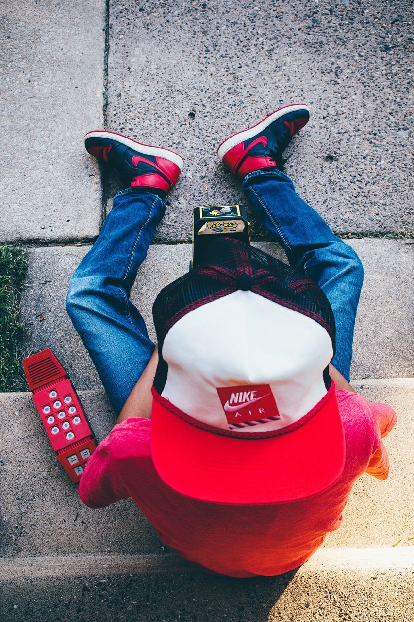 LOW SECTION OF MAN WEARING CANVAS SHOES ON ASPHALT