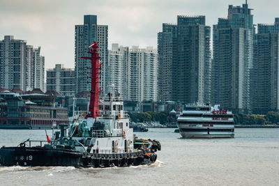 Boats in sea against buildings in city