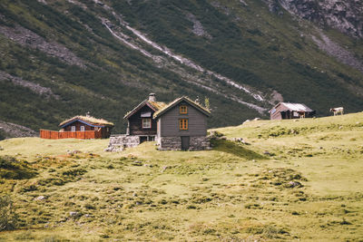 Houses on field by mountain