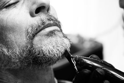 Cropped hand of barber trimming beard of man at salon