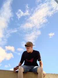 Low angle view of boy sitting against sky