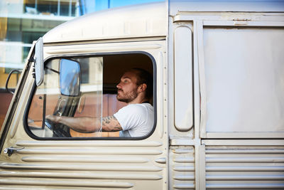 Side view of young male owner driving food truck in city