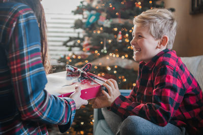 Cheerful woman gift to son at home during christmas 