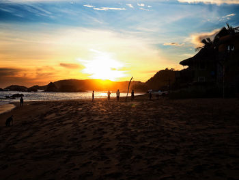 People on beach against sky during sunset