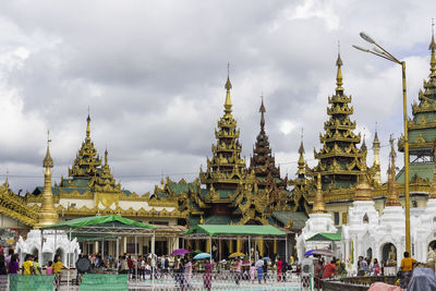 People at temple against cloudy sky