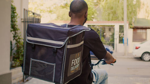 Rear view of man with suitcase on street