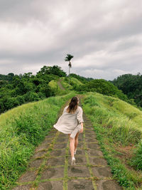 Rear view of woman standing on field against sky