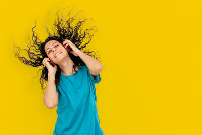 Young woman smiling against yellow background