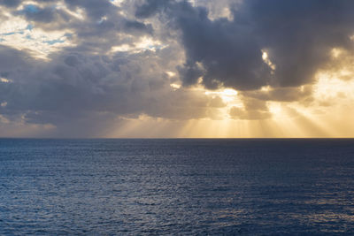 Scenic view of sea against sky during sunset with sunrays visible