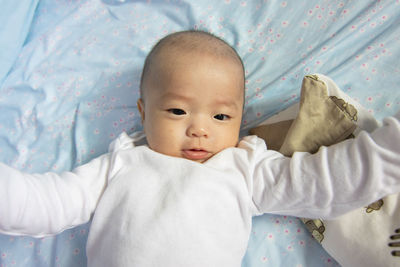 Portrait of cute baby lying on bed