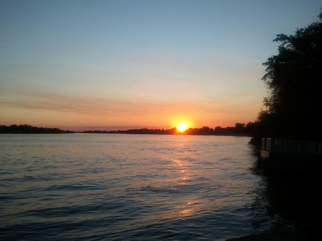 sunset, sun, water, tranquil scene, scenics, tranquility, beauty in nature, silhouette, reflection, waterfront, sky, sunlight, lake, nature, orange color, idyllic, river, tree, rippled, sunbeam