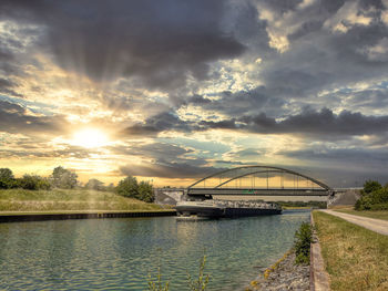 Bridge over river against sky during sunset