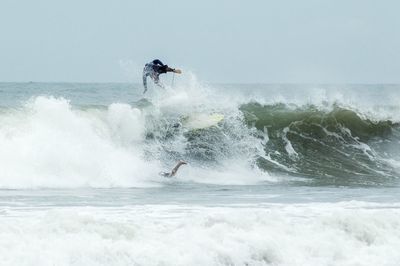 Man surfing in sea against sky