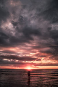 Silhouette man standing on beach against sky during sunset