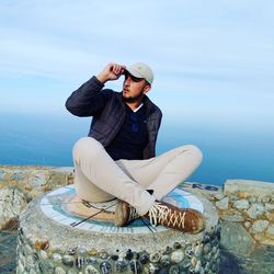 Full length of man sitting against sea