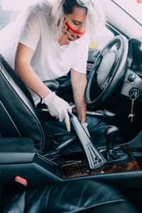 Woman cleans car interior with vacuum cleaner