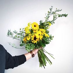 Close-up of hand holding bouquet against white background