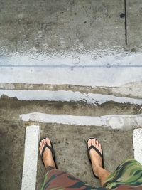 Low section of man standing on road during rainy season