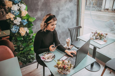 Young woman using mobile phone while sitting on table