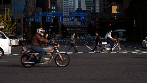 People riding vehicles on road in city