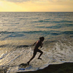 Full length of man on beach against sky during sunset