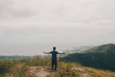 Rear view of man standing on field against sky