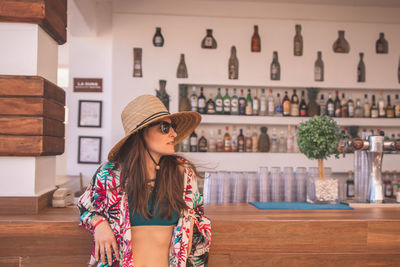 Woman wearing hat standing against wall