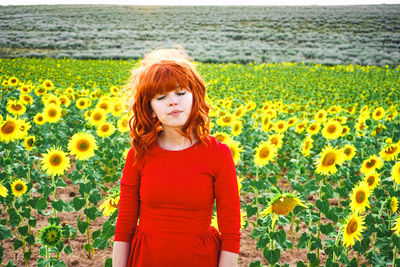 Smiling young woman with yellow flowers in field