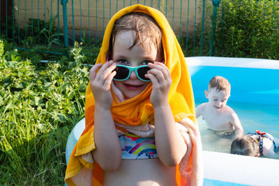 Wet and cheerful child in a towel and sunglasses near the pool. summer is a time of pleasure and fun
