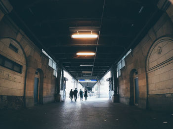 Rear view of people walking out from walkway under bridge