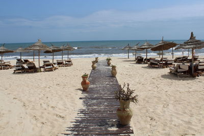 Deck chairs on beach against sky