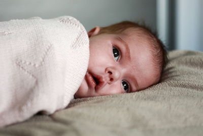 Close-up of cute baby lying on bed