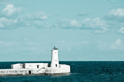 Lighthouse by sea against sky