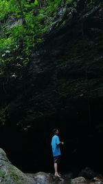 Full length of woman standing on rock in forest