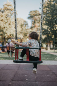 Rear view of girl sitting on swing at playground