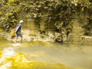 Man walking in water by rock formation