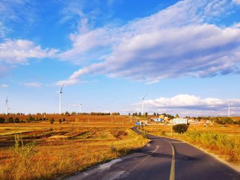 Road amidst field against sky