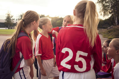 Soccer girls talking on footpath against sky