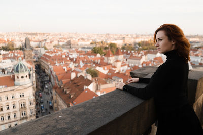 Side view of woman standing by cityscape in city