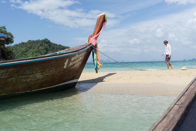 Boat moored on beach against sky