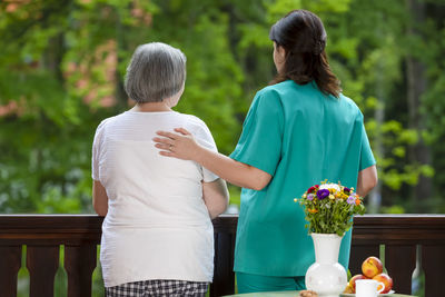 Rear view of couple standing by flowering plants