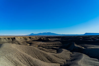 Panoramic view of desert against clear blue sky