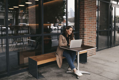 Adult business woman freelancer works using wireless technology talking on the phone sitting in cafe