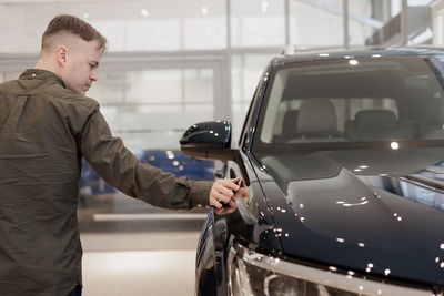 Side view of man holding car