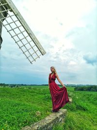 Woman with umbrella on field against sky