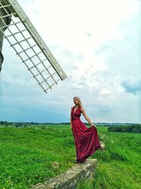 Woman wearing dress standing on land against cloudy sky